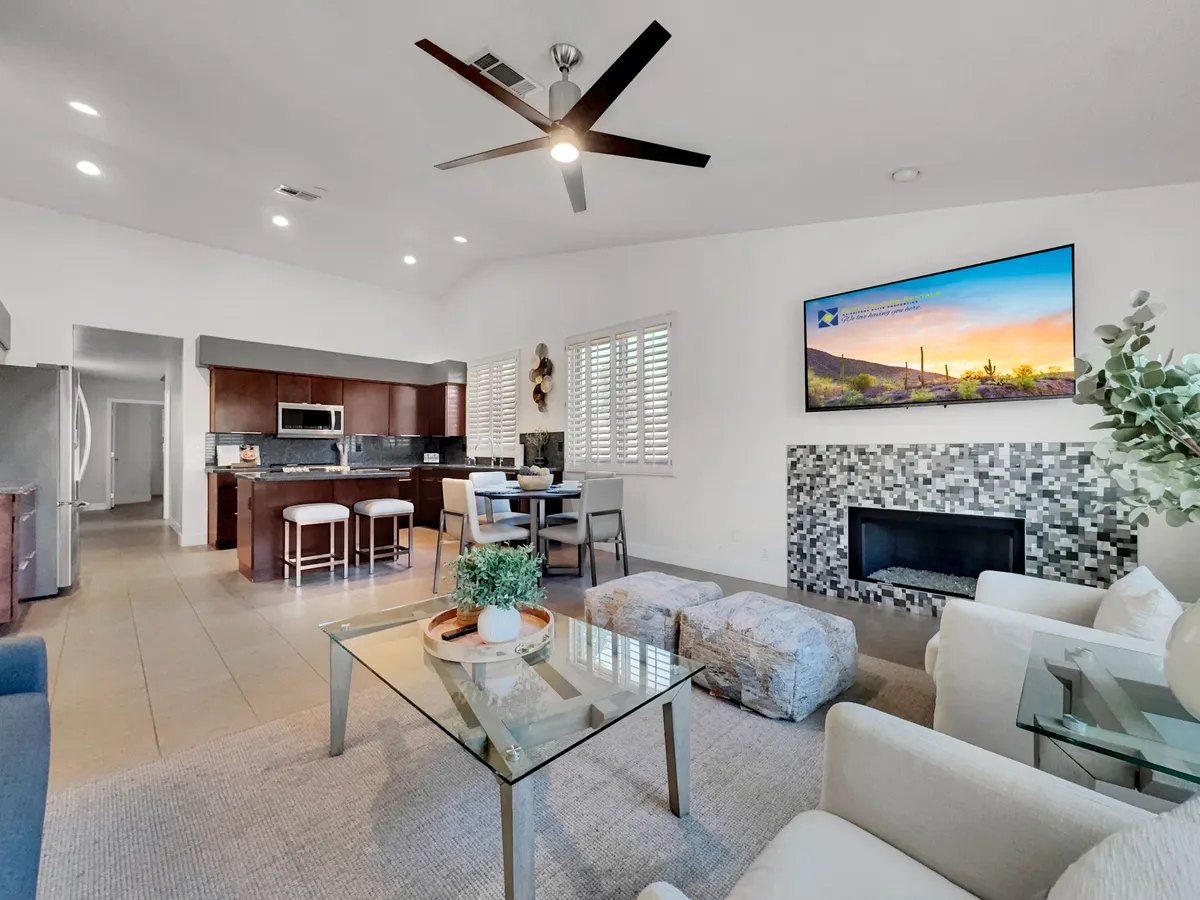 An open-plan living area that connects a comfortable sofa and coffee table with a visible kitchen space and TV, suggesting an environment conducive to gatherings, dining, and relaxing together.