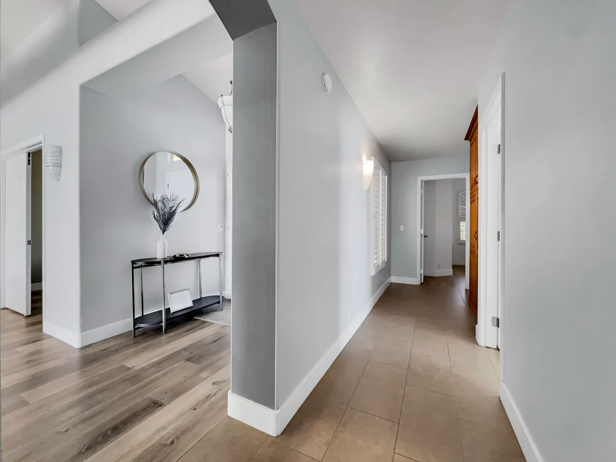 This entryway features a console table, mirror, and visible doorways, creating an inviting first impression. The space feels welcoming and hints at transitions between the home’s interiors and the world outside.