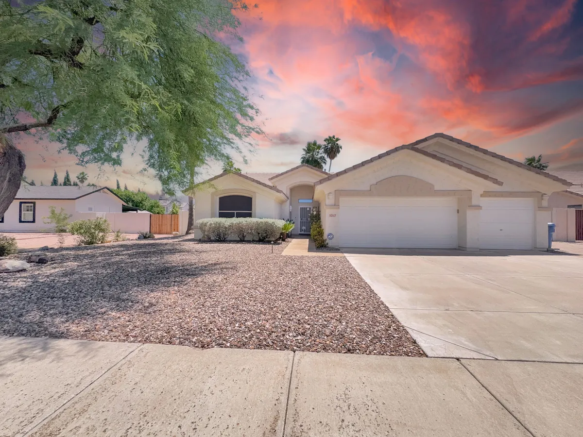 This image showcases the home's front entrance framed by lush landscaped bushes and a spacious driveway. The scene is inviting and hints at the property's welcoming environment for family gatherings and outdoor activities.