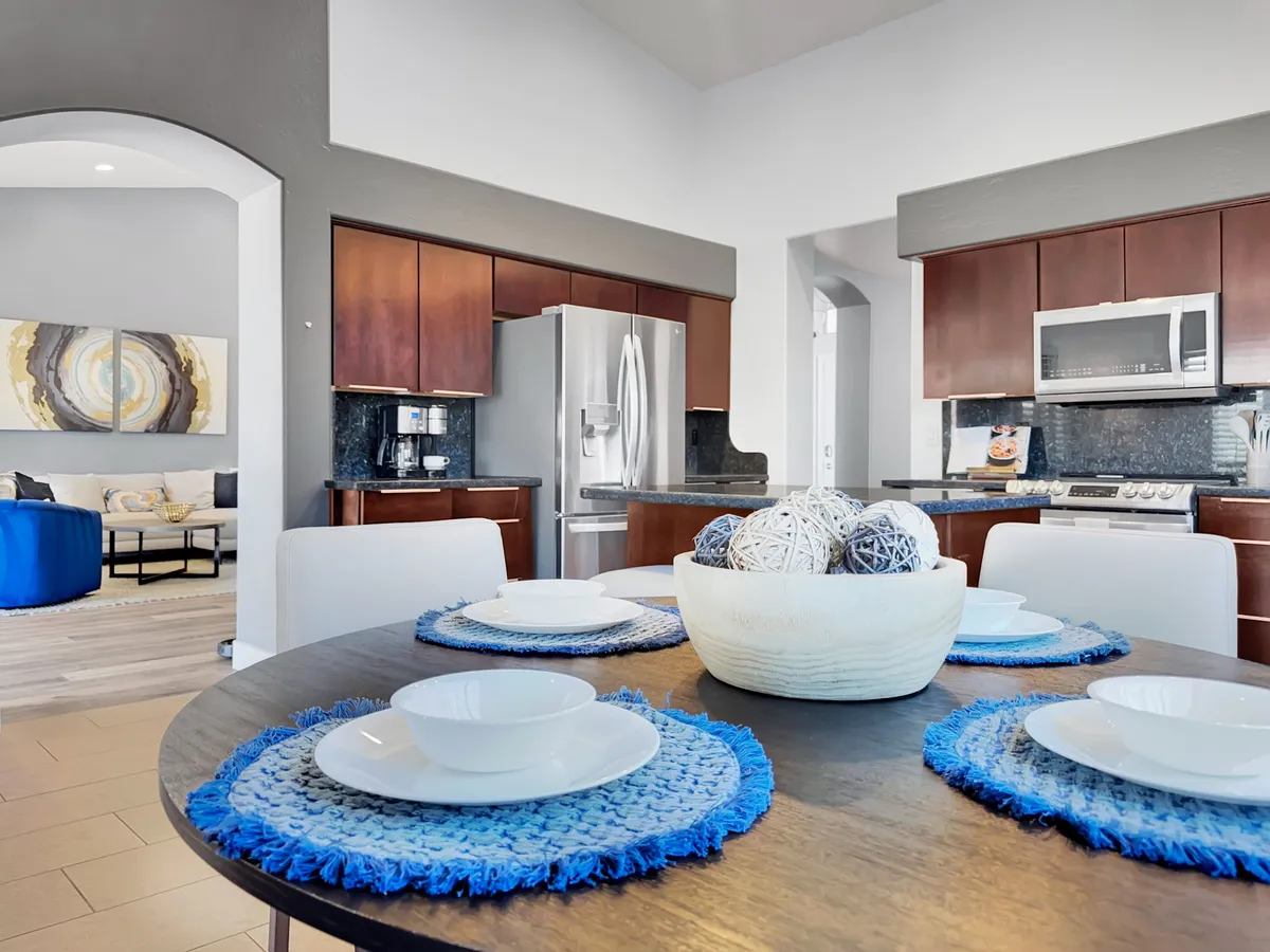 An inviting dining area with a table set for a meal, seamlessly connected to the kitchen. Visible kitchen appliances and a decorative bowl create a sense of readiness for both casual and festive dining occasions.