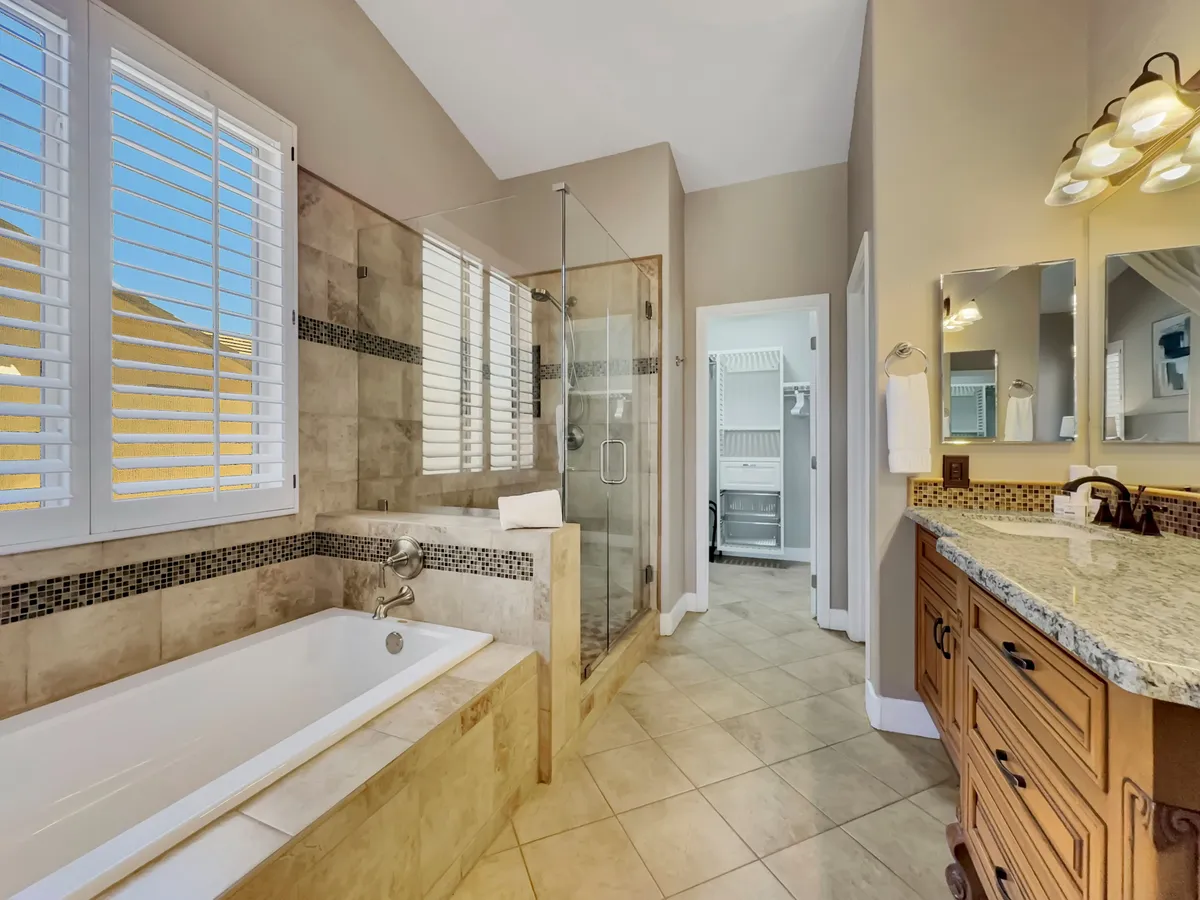 A spacious, modern bathroom with a freestanding bathtub, a glass shower enclosure, and a double sink vanity. The neutral palette and natural light add to the tranquil, spa-like ambiance, perfect for relaxation and privacy.